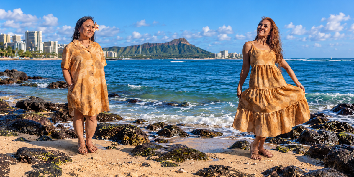Two models in ʻOpihi print dresses on the beach with Diamond Head behind